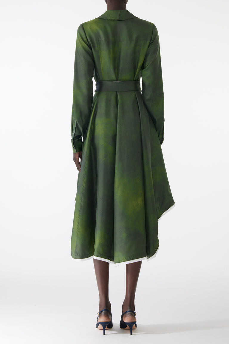 Model wearing a green silk twill shirtdress with long sleeves, asymmetric skirt, matching belt, and white-edged hem. view 3