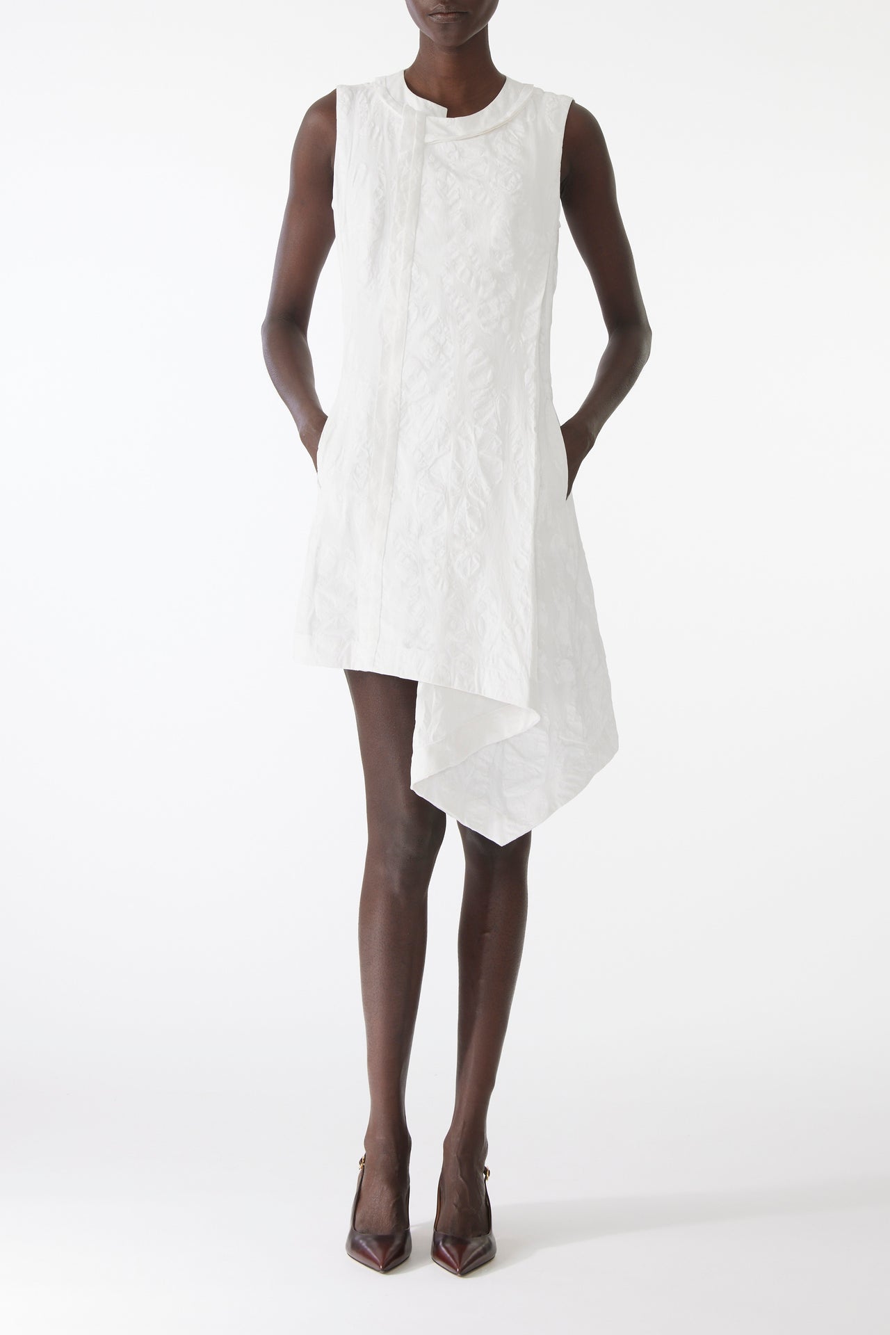 Model wearing mini dress in textured cotton with burnt dot print, featuring a clean neckline and asymmetrical hem. view 1