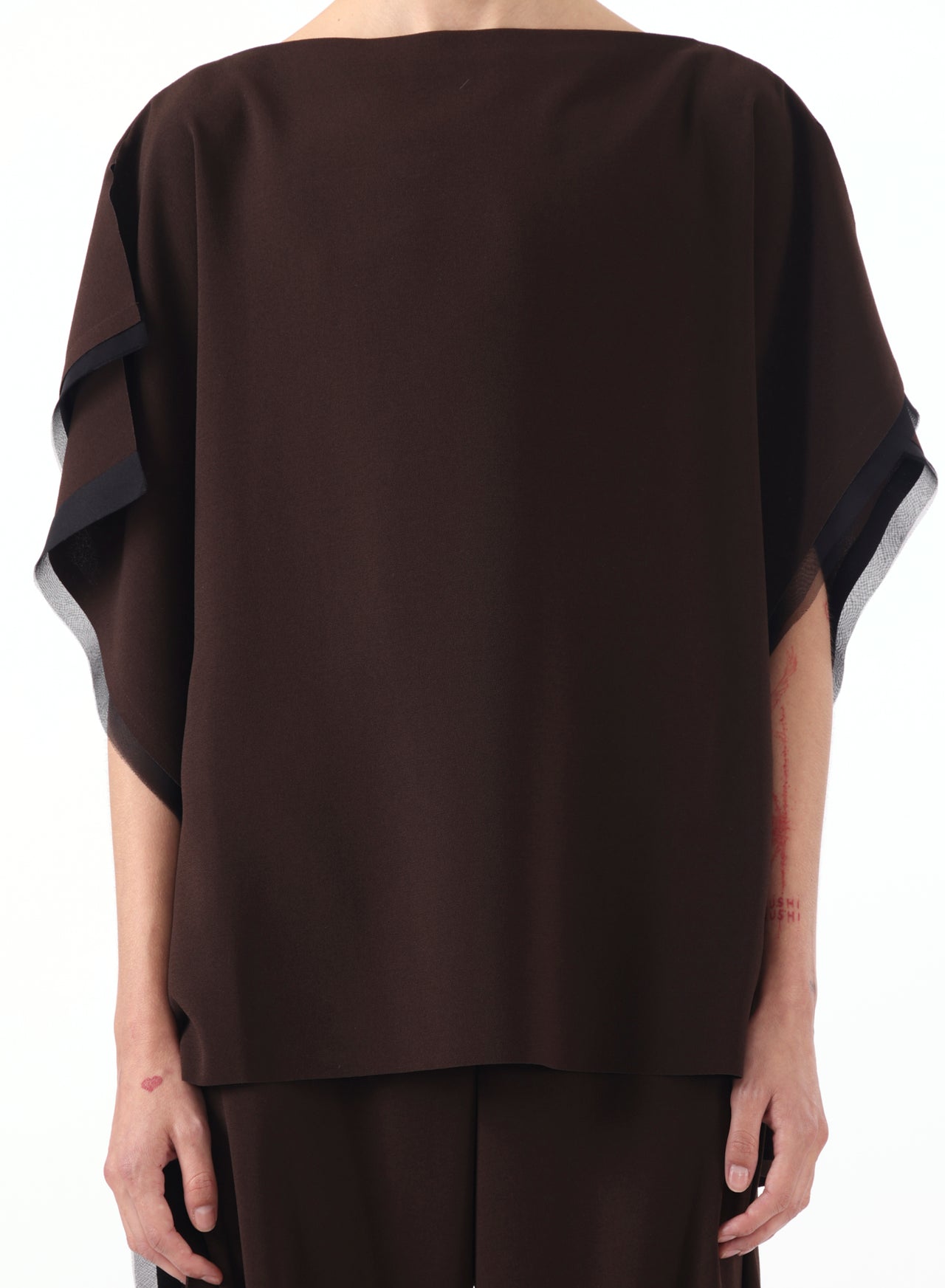 Model wearing an asymmetrical crepe boatneck top with organza trim detailing. view 1