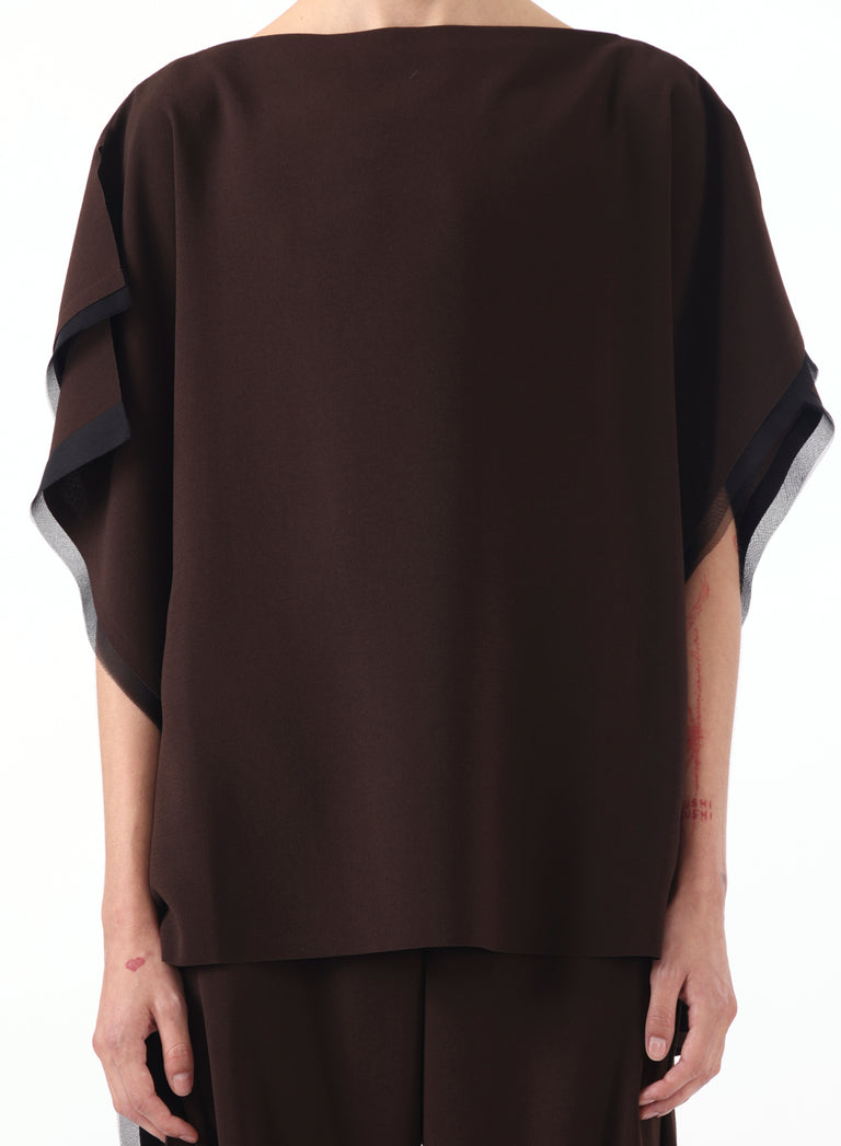 Model wearing an asymmetrical crepe boatneck top with organza trim detailing. view 1