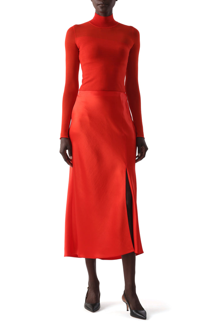 Model wearing a papaya-colored top with soft draping and minimalist detailing. view 1