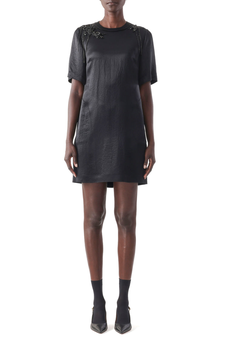 Model wearing a black short sleeve dress with embroidered appliqués and a sleek fit. view 1
