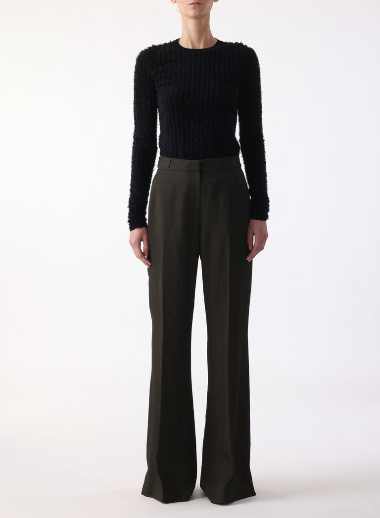 Model in nori green flare suiting pants with a clean front and back leg slits. view 1