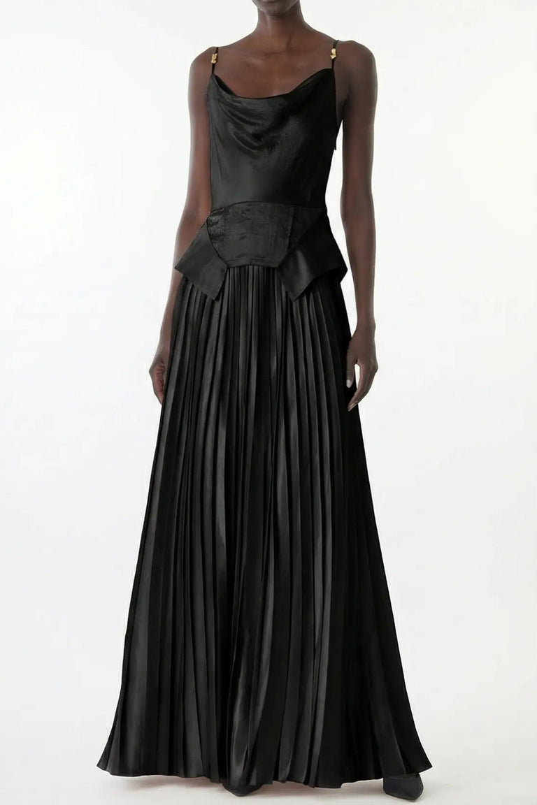 A model wearing a black satin-like maxi dress with a draped bodice, structured peplum waist, and a voluminous pleated skirt, photographed against a plain white studio background. view 2