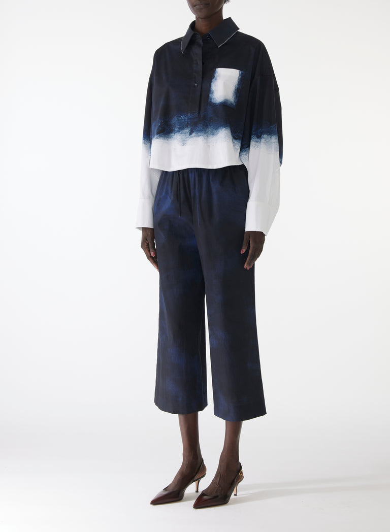 Model wearing wide-leg stretch cotton pants with elastic waistband and navy-and-white smudged print, styled with matching pop-over shirt. view 2