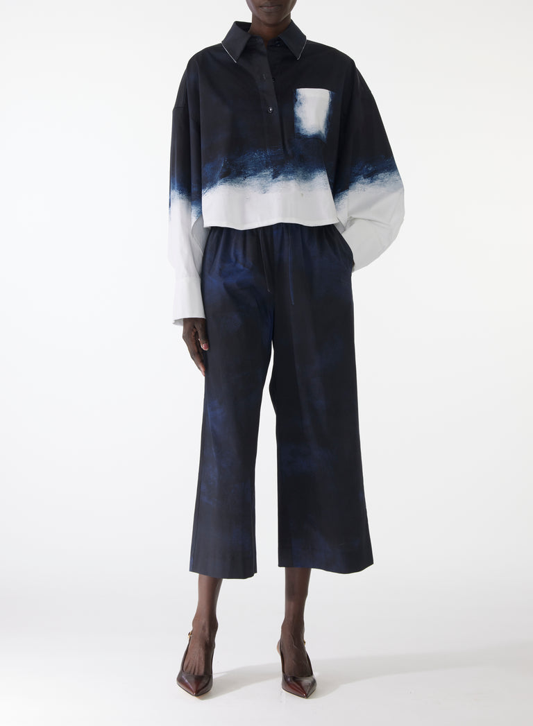 Model wearing wide-leg stretch cotton pants with elastic waistband and navy-and-white smudged print, styled with matching pop-over shirt. view 1