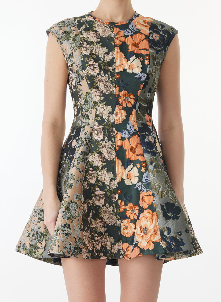 A sleeveless fit-and-flare dress with a floral print, featuring a dark green base with orange, beige, and blue floral patterns, shown on a model against a white background. view 3